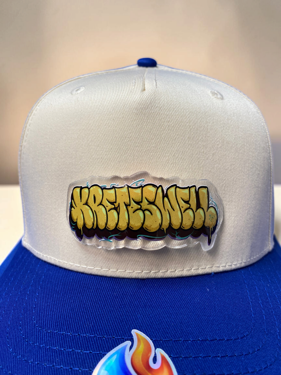 Gold Kreteswell wordmark Drop on a blue and cream hat